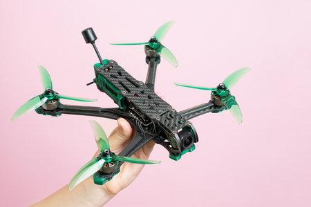 Hand holding a modern drone with camera isolated on pink background