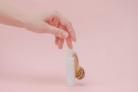 A Cosmetic's bottle and snail on it with elegant hand. Skin care, spa, luxury cosmetic, natural beauty productの写真素材