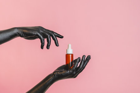 Brown glass bottle with the black painted elegant woman's hands on her skin. Presenting luxury, fashion skincare productsの写真素材