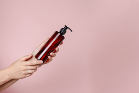 Blank bottle mockup in hand isolated on the solid red background. Package for cosmetics product, spa, beauty and luxury. Space for textの写真素材