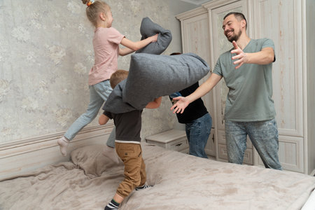 Smiling family plays with kids with the pillows. Happy family momentsの写真素材