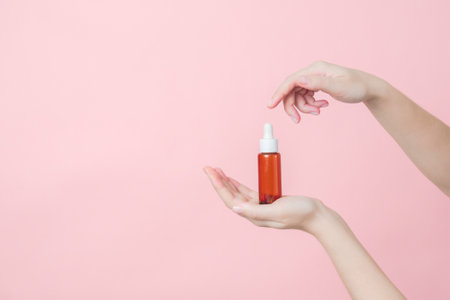 Hand holds serum glass brown bottle with pipette.の写真素材