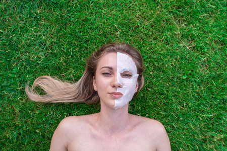 Young woman with face mask lying down in the green grass. Healthy, naturally
