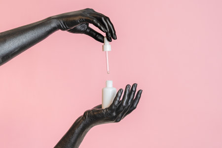 Black painted elegant woman's hands on her skin with a white cosmetic bottle. High Fashion art...