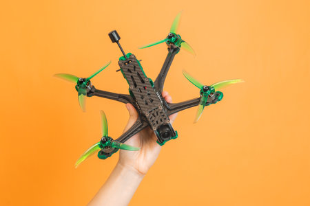 Hands holding a professional modern drone with camera on orange background