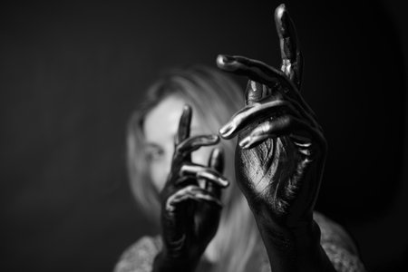 A Young woman with hands in paint at black background. Fashion, artistic conception