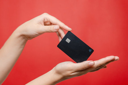 Close up blank credit card with online service for mockup in hand on a pink background. Modern way of banking and buyingの写真素材