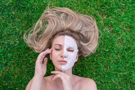 Close up of woman's face with cosmetic face mask in the grass. Spa, healthy, naturally. Healthy lifestyle conceptの写真素材