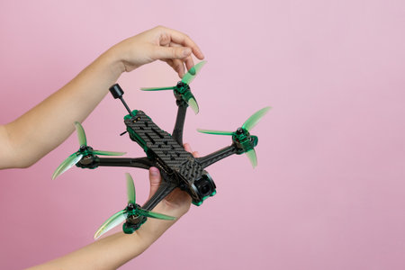 Hand holding a modern drone with camera isolated on pink background