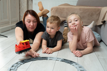 Smiling mother plays with children on a floor. Happy family momentsの写真素材