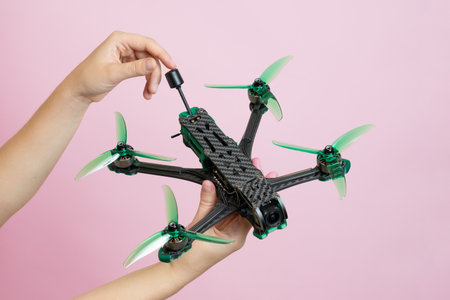 Hand holding a modern drone with camera isolated on pink background