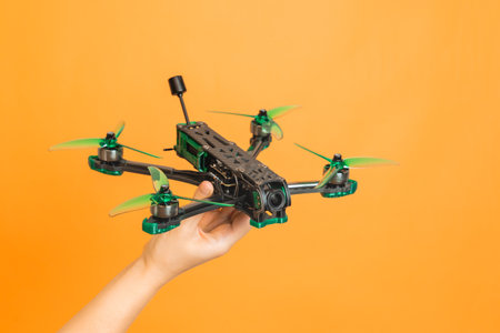 Professional modern drone with a camera in hands isolated on orange background