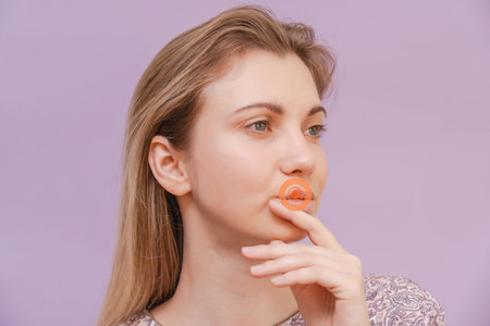 Closeup of a young woman herpes touching lips with purple background. Herpes blistersの写真素材