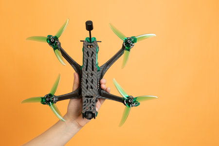 Professional modern drone with a camera in hands isolated on orange backgroundの写真素材