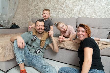 Happy family sitting on the couch at home. Mother, father and children.の写真素材