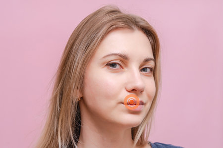 A Closeup on mouth of young woman with pink background.の写真素材