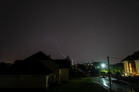 Lightning striking over suburban street and houses during a dark, stormy night