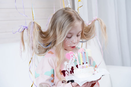 Smiling small blond girl have holiday at home with a cake. Decoration and photo zone for girls party. Happy birthdayの写真素材