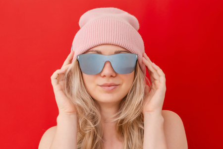 Young woman posing in stylish winter accessories on a red background