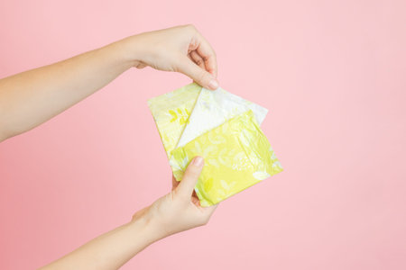 Packed sanitary napkins in a hand. Menstruation cycle, feminine hygiene and protection. Flat layoutの写真素材