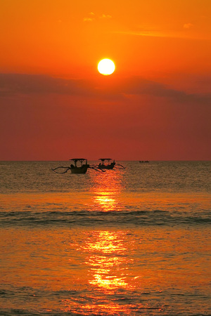 Red sun orange ocean sunset with fisherman boats silhouettes, Kuta beach, Bali, Indonesiaの写真素材
