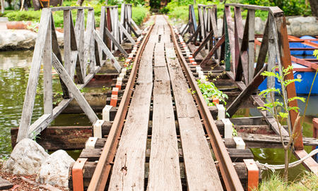 Small railroad tracks made of steel and wood build a bridge over the water canal.の写真素材