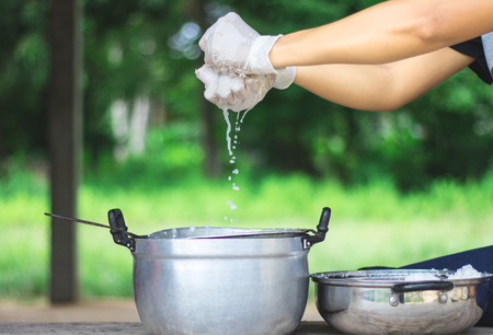 Close up view. Hands person are crushed coconut milk put into an old pot with a sieve for filtering.の写真素材