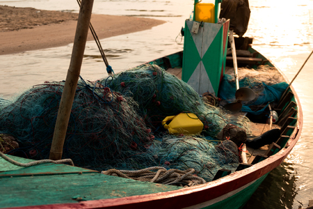 Fishing nets and equipment are in the old boat on sandy beaches. With warm sunlight of morning.の写真素材