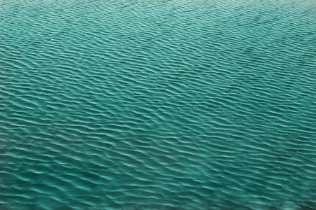 Pale blue and green water surface has waves patternの写真素材