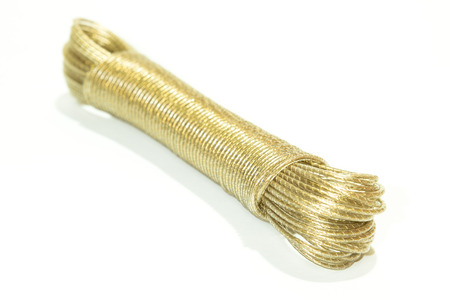 Close up view of yellow coiled rope tied neatly stored. Isolated on white floor.