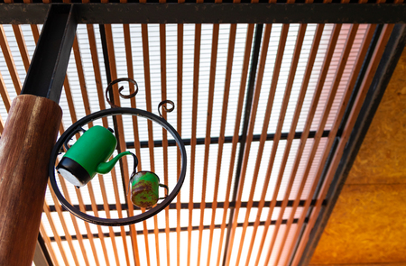 Perk view and low light of old pot with green cup hung on a wooden pole. For coffee shop decoration in vintage style.の写真素材