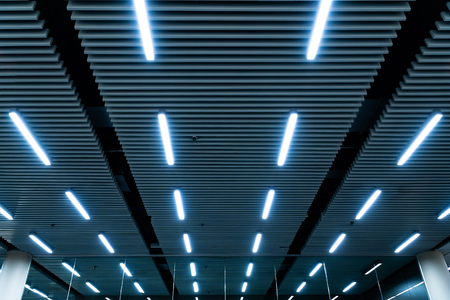 Leading lines and low light view. Fluorescent lamps open in row on the ceiling beautiful and modern...