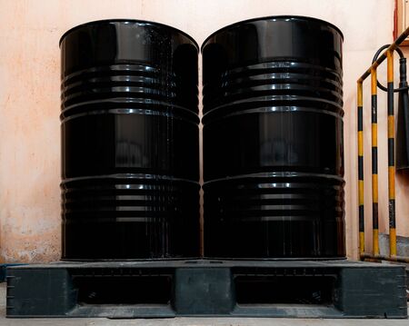 Low light inside of factory. Two black tanks chemical packaging with old and stained.の写真素材