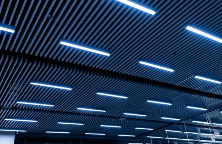 Leading lines and low light view. Fluorescent lamps open in row on the ceiling beautiful and modern...