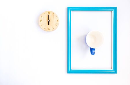 Top view and copy space of clock made wooden. And blue picture frame with a cup inside. Placed on white background.の写真素材
