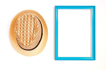 Top view of blue picture frame wooden with inside empty space. And woven hat made from natural...