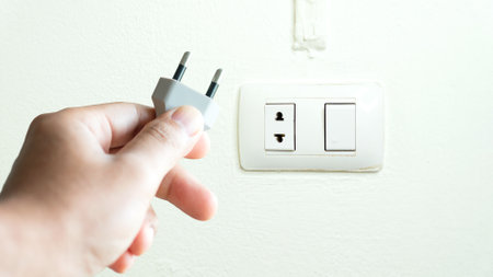 Close up view. A hand pick up two pin electrical plug. To be plugged into an socket that two hole...