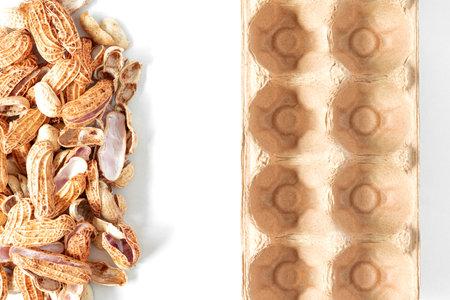 Top view and close up on white floor. Husk of peanuts with empty egg carton boxes. The concept is to process nut shell waste to be natural packaging.の写真素材