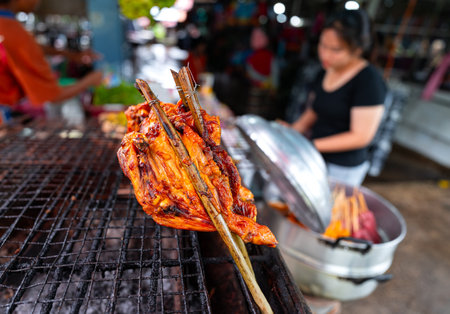 Close up of grilled chicken with tongs on a grill. It is a popular food among Thai people.の写真素材