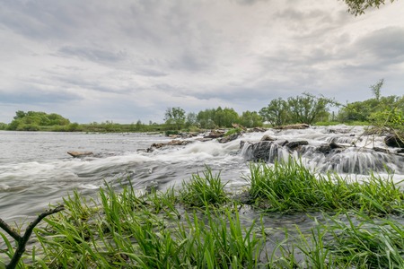 Summer landscape. River, riverside and sky. Rolls on a mountain river under the blue skyの写真素材