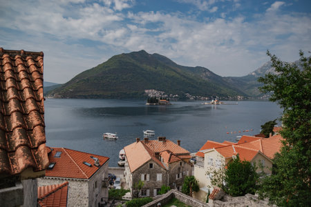 Scenic panorama view of the historic town of Perast at famous Bay of Kotor with mountains on a beautiful sunny day with blue sky and clouds in summer, Montenegro, southern Europeの写真素材