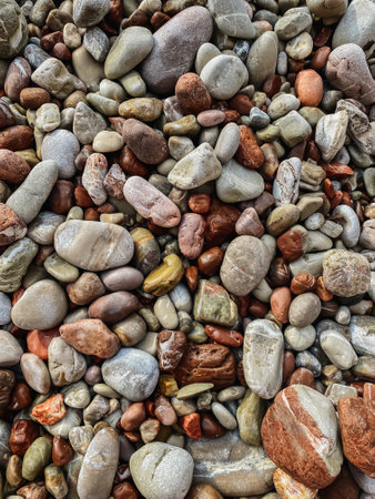 Pebbles on the beach, as abstract background. Small colorful stones wallpaper. Sea stones with...