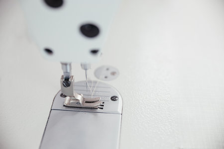 Close up picture of sewing-machine in white color. Macro sewing needle in fashion design atelier....