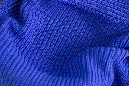 Knitted warm blue sweater. Cozy composition in the home atrosphere. Wool fabric texture close up...