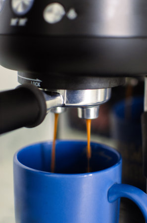 Home espresso machine pouring fresh coffee in blue mug. Close up picture of modern home espresso machine, as home barista concept.の写真素材