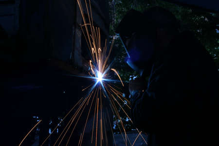 Welder welds metal on machine with sparks. High quality photo