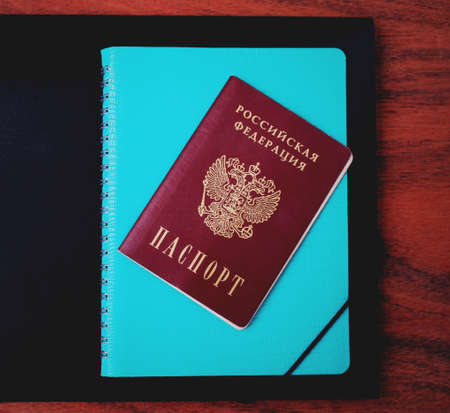 Blue diary, passport and black folder on the background of a wooden tableの写真素材