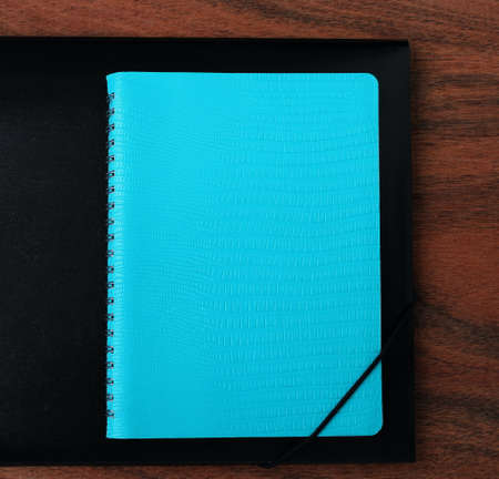 Blue diary and black folder on the background of a wooden table