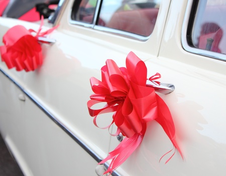 a vintage white wedding car with red ribbonの写真素材
