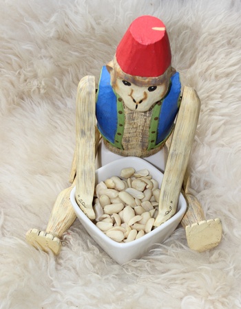 A wooden monkey wearing a fez eating nutsの写真素材